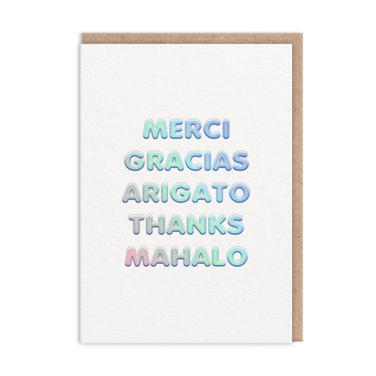 Thank you card with thank you in different languages. Text finished in holographic foil reads "Merci Gracias Arigato Thanks Mahalo"