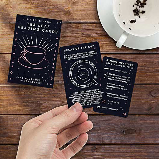 Person holding 2 of the tea leaf reading cards